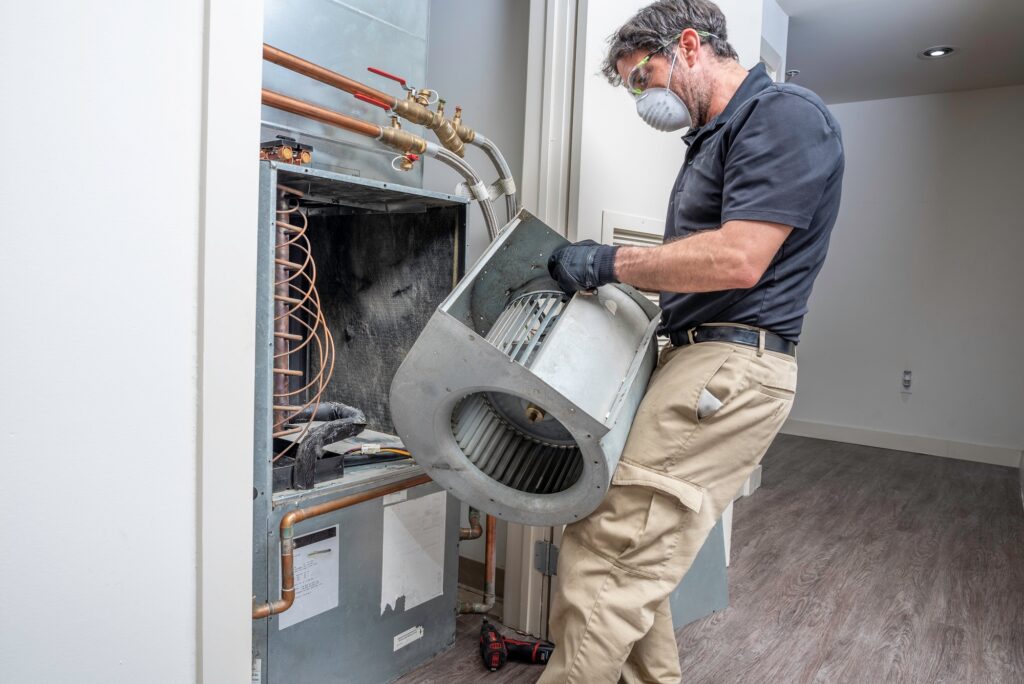 A man with a mask performing a service on a furnace.